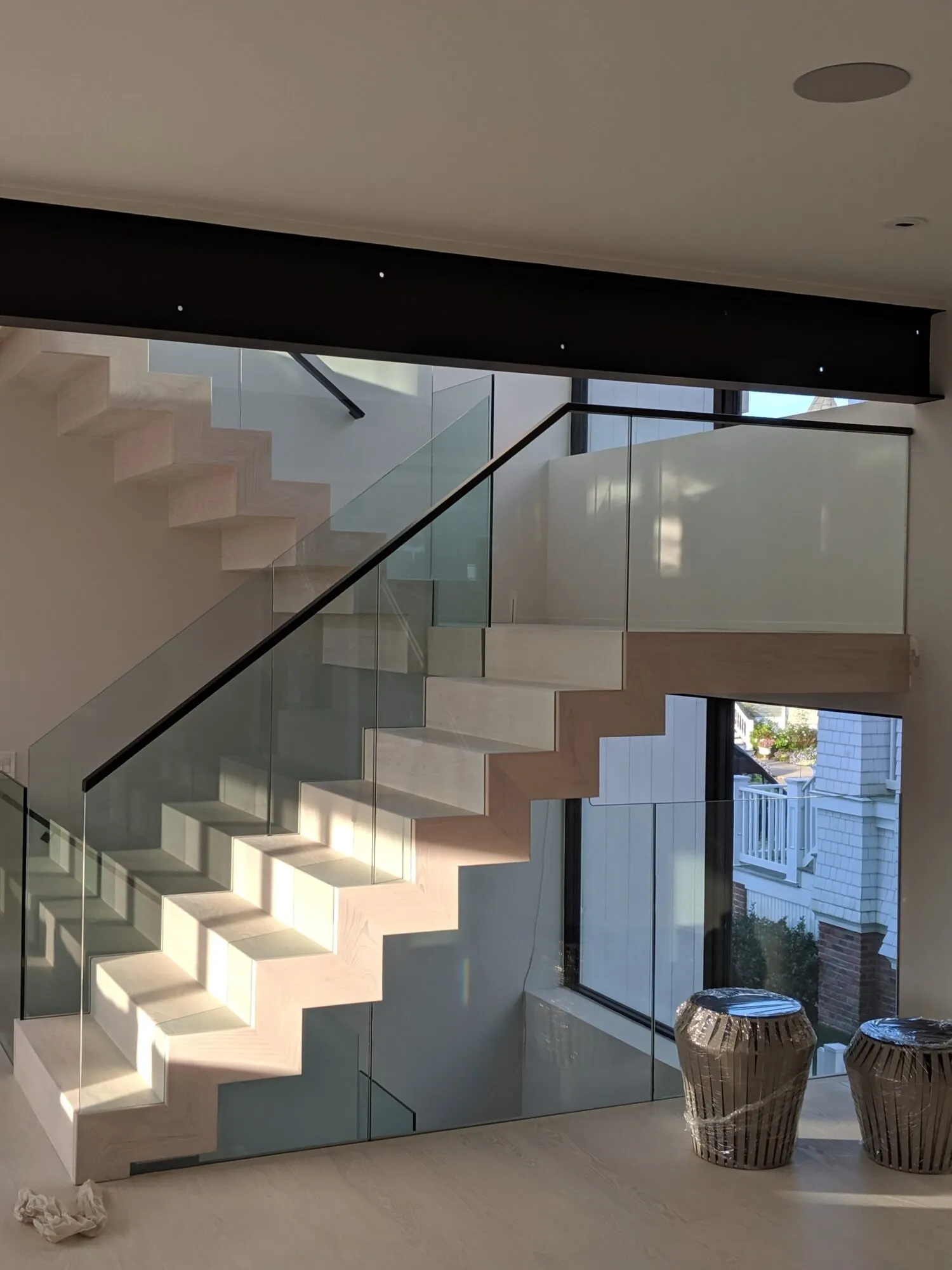 Modern floating staircase with pale wood treads and a frameless glass railing — cover image for the Bucks County Stairs & Millwork website project