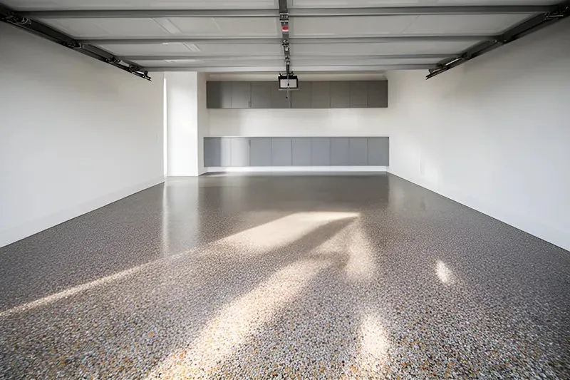 Empty two-car garage with a glossy, speckled flake-coated concrete floor and white walls — cover image for the ConcreteCoatings.com website project