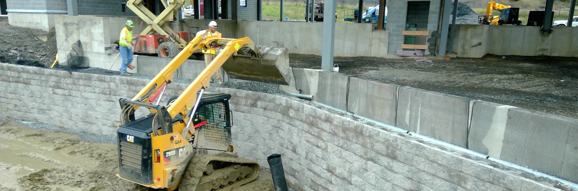 Crew operating heavy equipment to build a retaining wall on an active job site