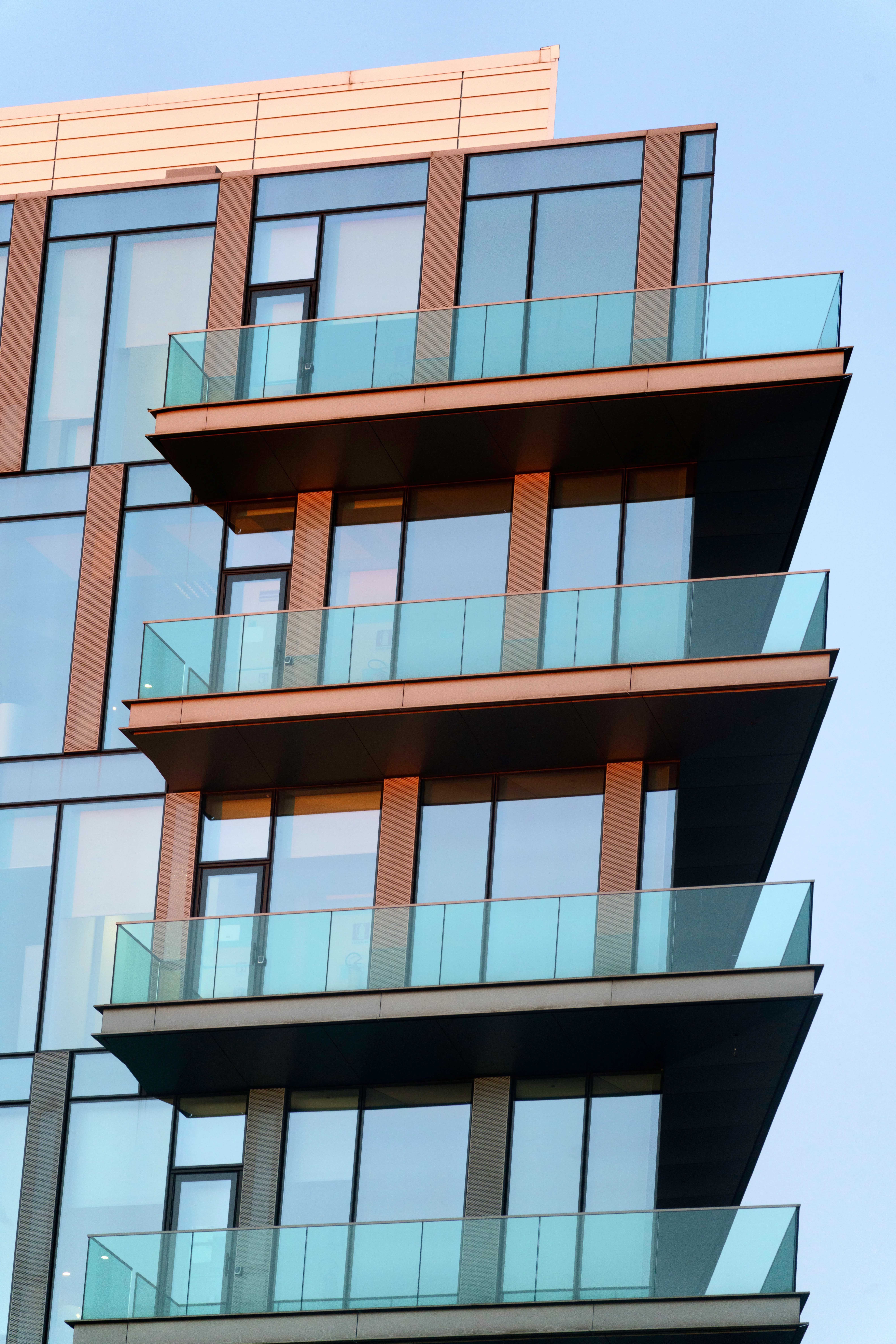 Modern glass apartment tower with cantilevered balconies at dusk