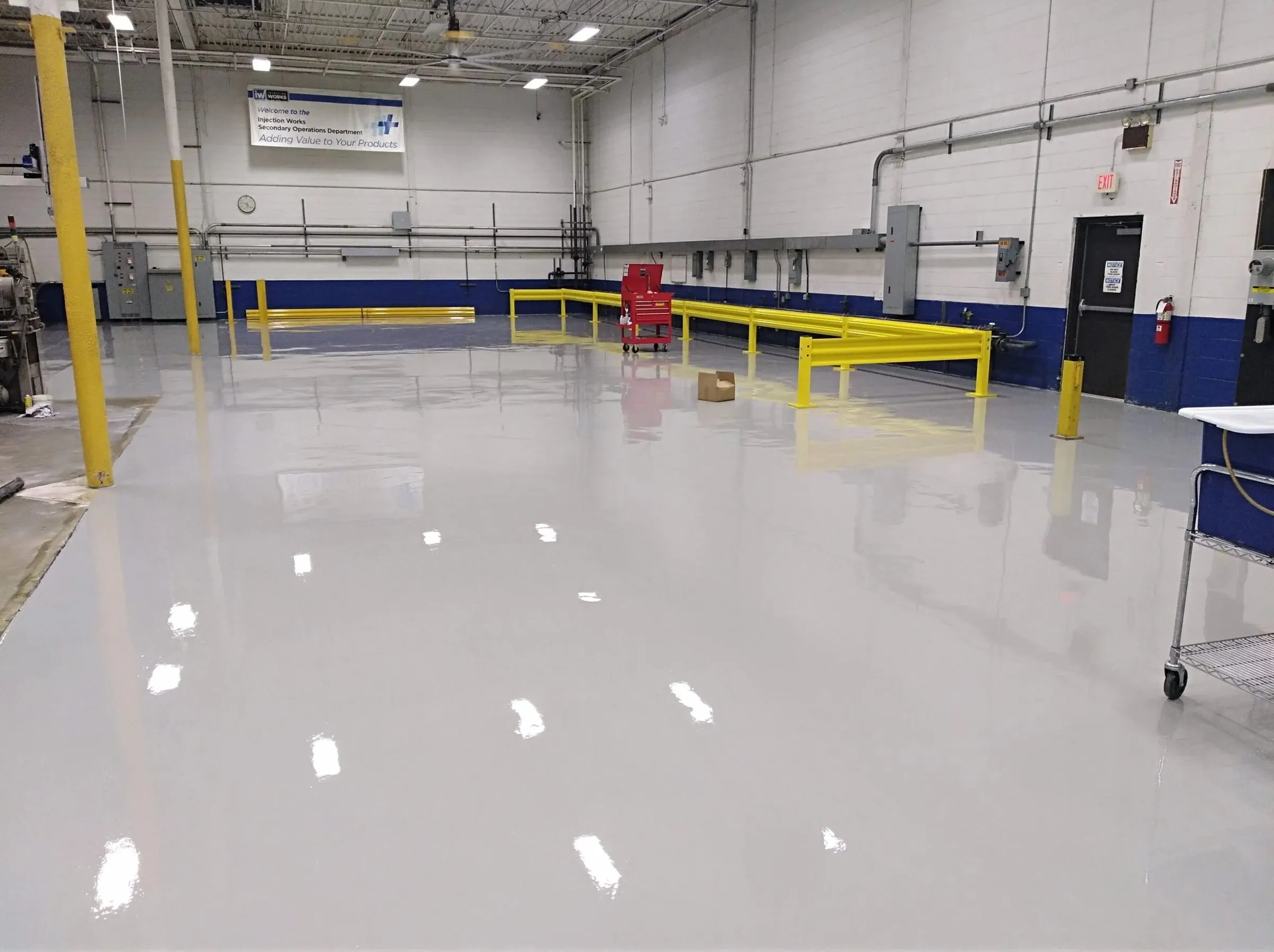 Industrial service bay with a glossy light-gray epoxy floor coating and yellow safety rails — cover image for the PolyTitan Coatings website project