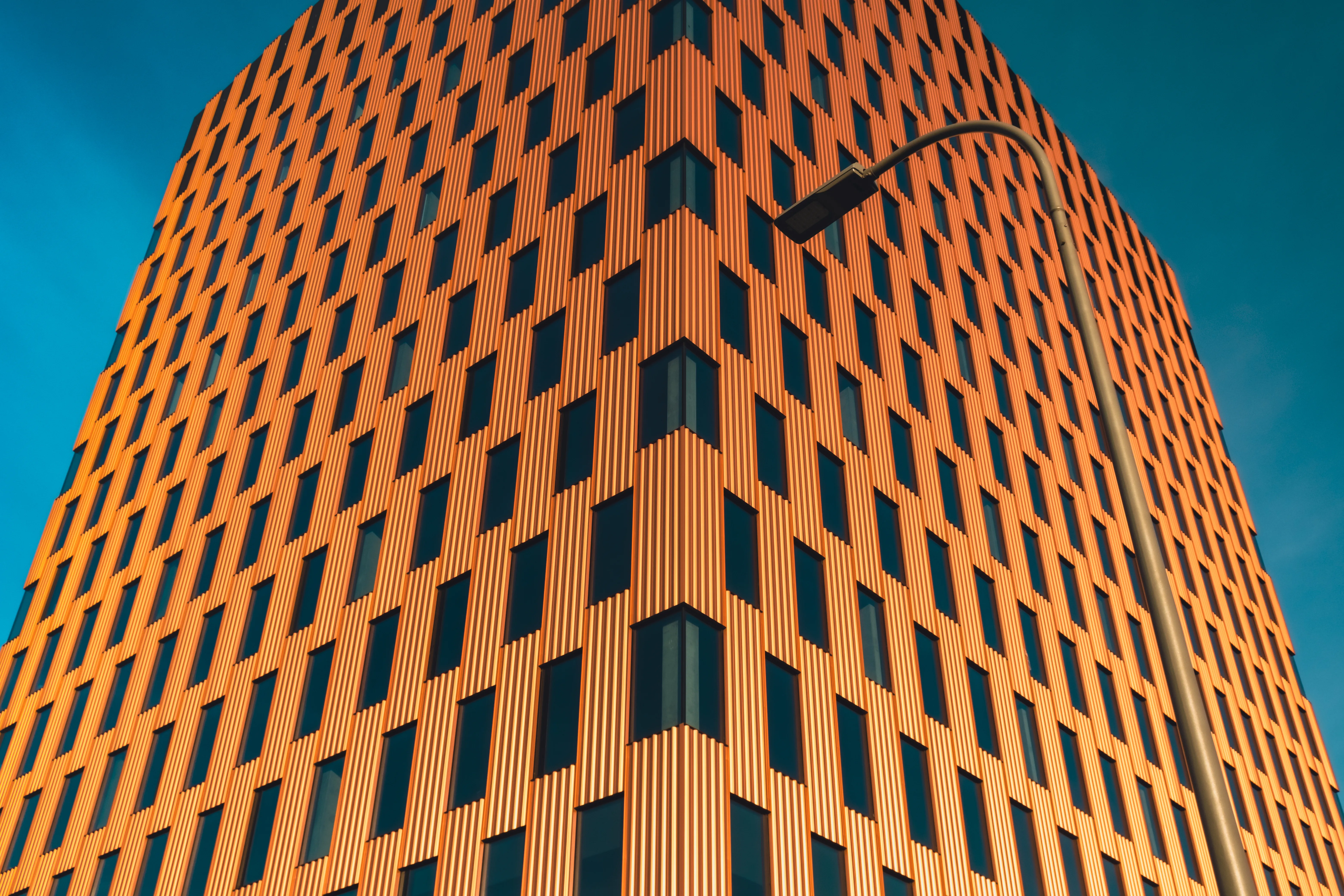 Angular high-rise office tower with warm copper-toned cladding against a blue sky