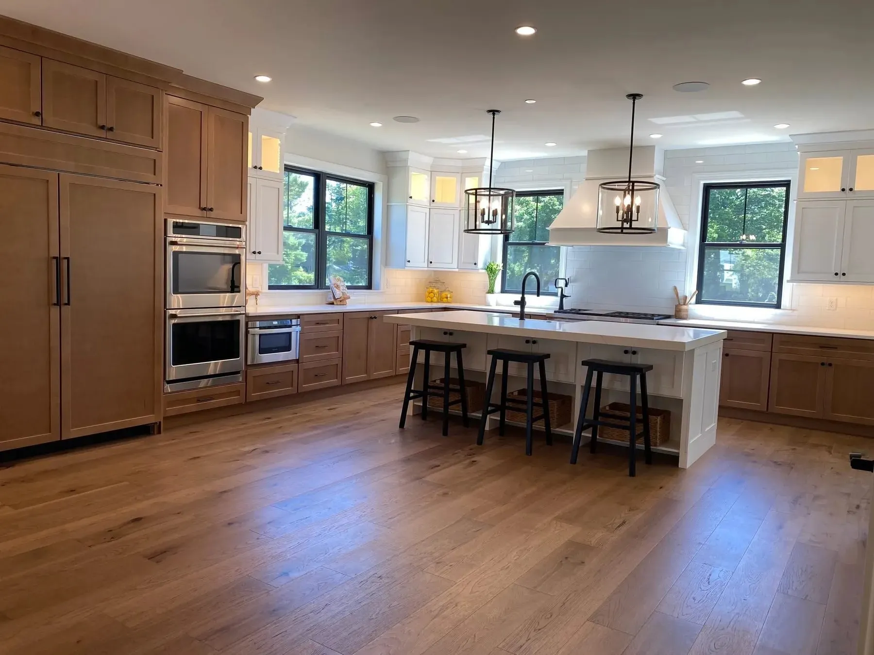 Newly finished kitchen with custom wood cabinetry, a large island with stools, pendant lights, and wide-plank oak floors — cover image for the ZBR Enterprises website project