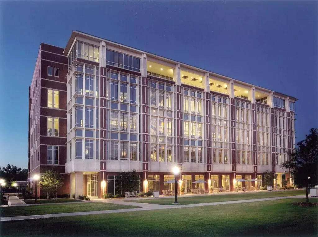 Six-story brick and glass campus building lit up at dusk, with a lawn and lamp-lined walkway in front — cover image for the ZFI Engineering website project